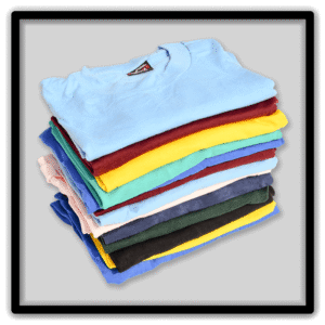 Tall stack of folded vintage blank T-shirts in assorted bright and neutral colors.